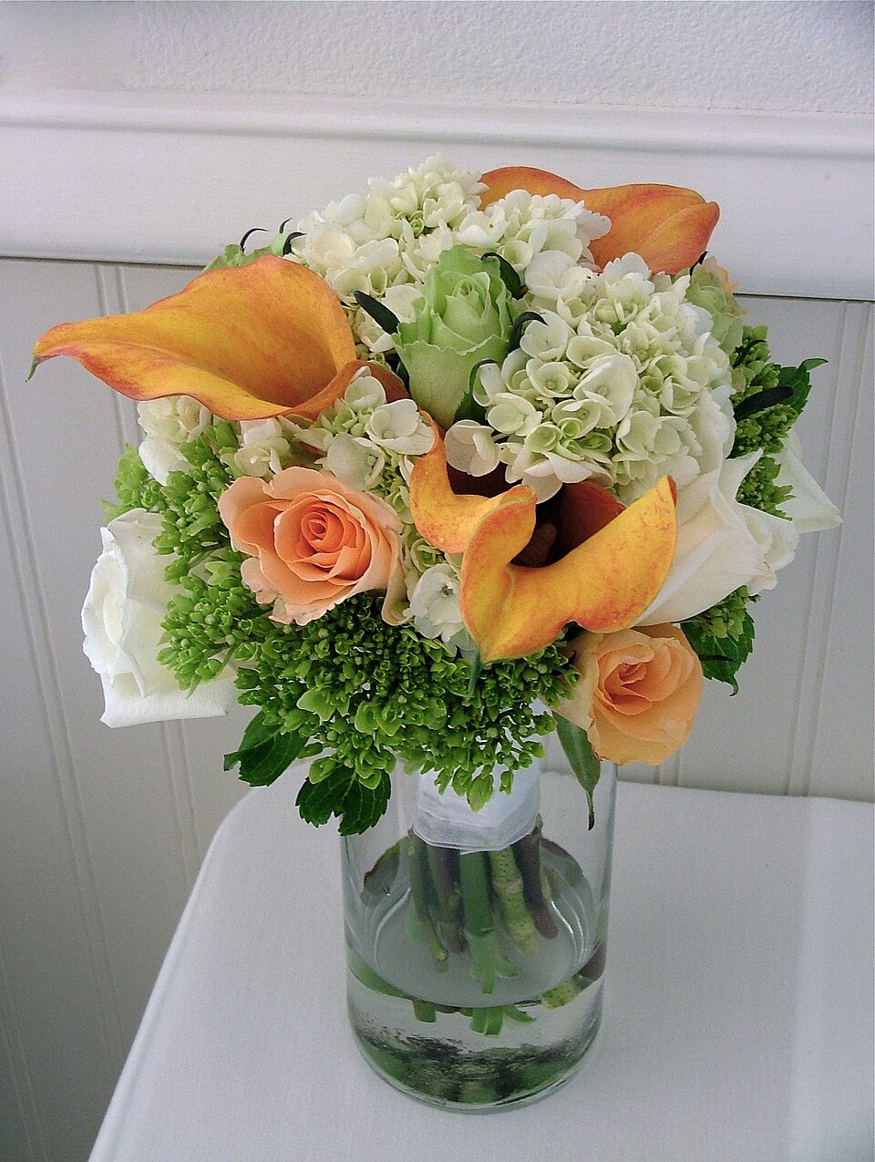 Arrangement with orange calla lilies, roses and green hydrangea